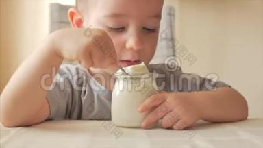 小男孩坐在桌子旁，独自用<strong>勺子</strong>吃婴儿食品。<strong>一个</strong>2-3岁的男孩急切地吃牛奶